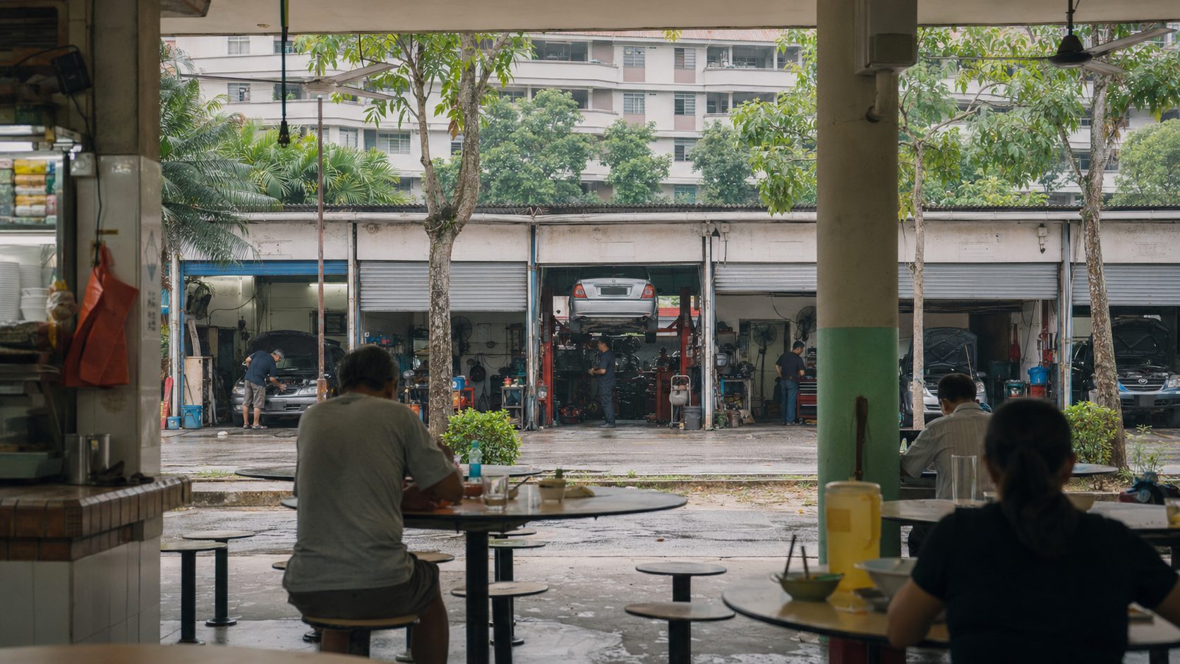 View from an open-sided hawker centre towards neighbouring motor-repair bays at Alexandra Village